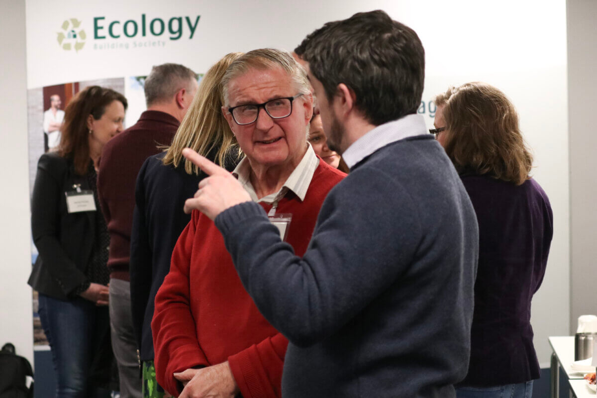 Two men speaking enthusiastically at the Ecology annual general meeting 2024.