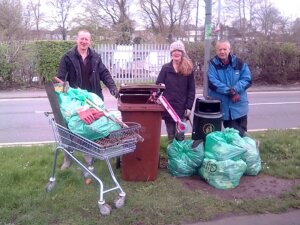 Volunteers with bags of collected litter and a shopping trolley used to carry waste during a local environment cleanup